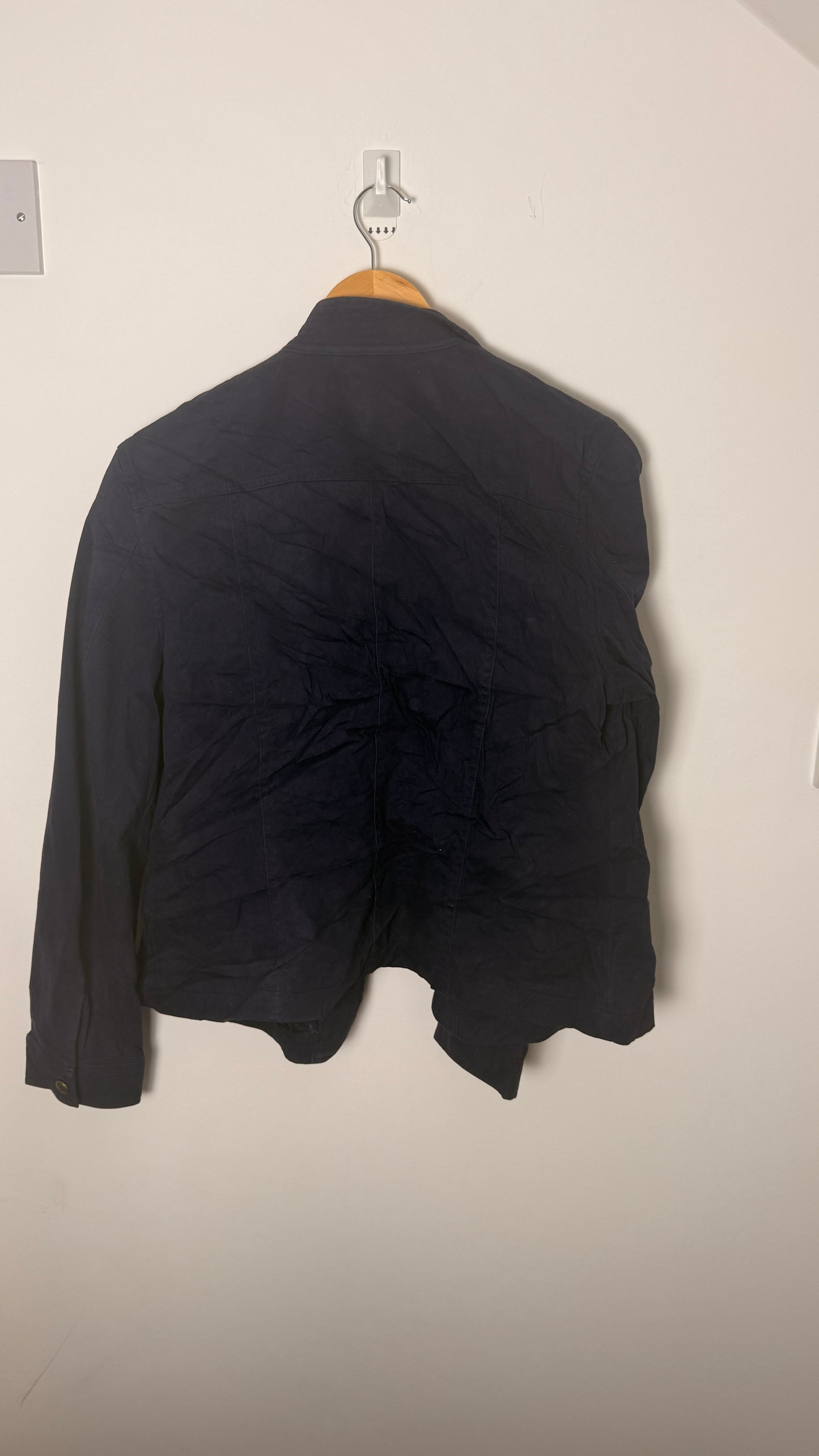 Black jacket on a hanger against a plain wall